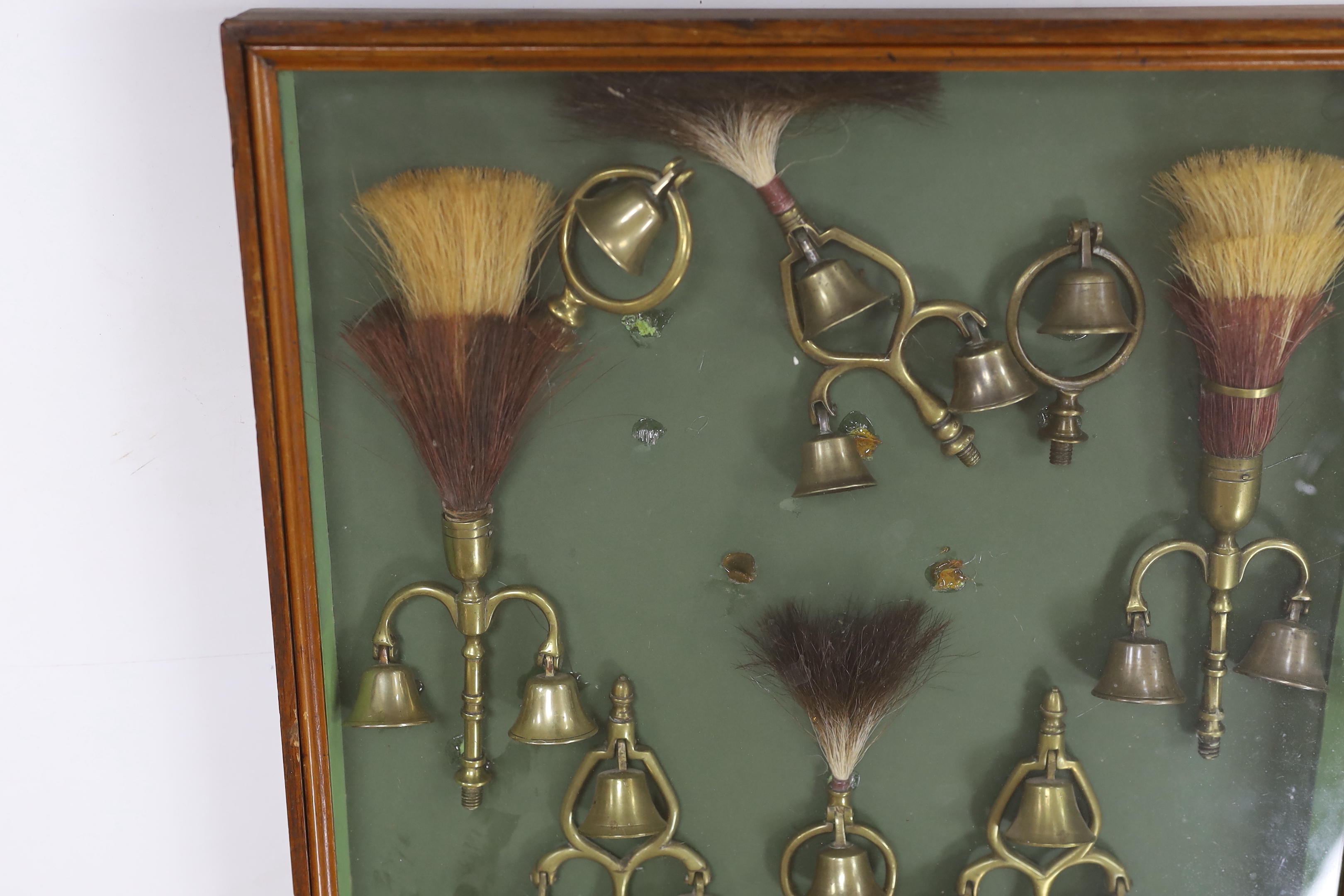 A collection of Victorian horse brass bell terrets, housed in a display case, 46cm high